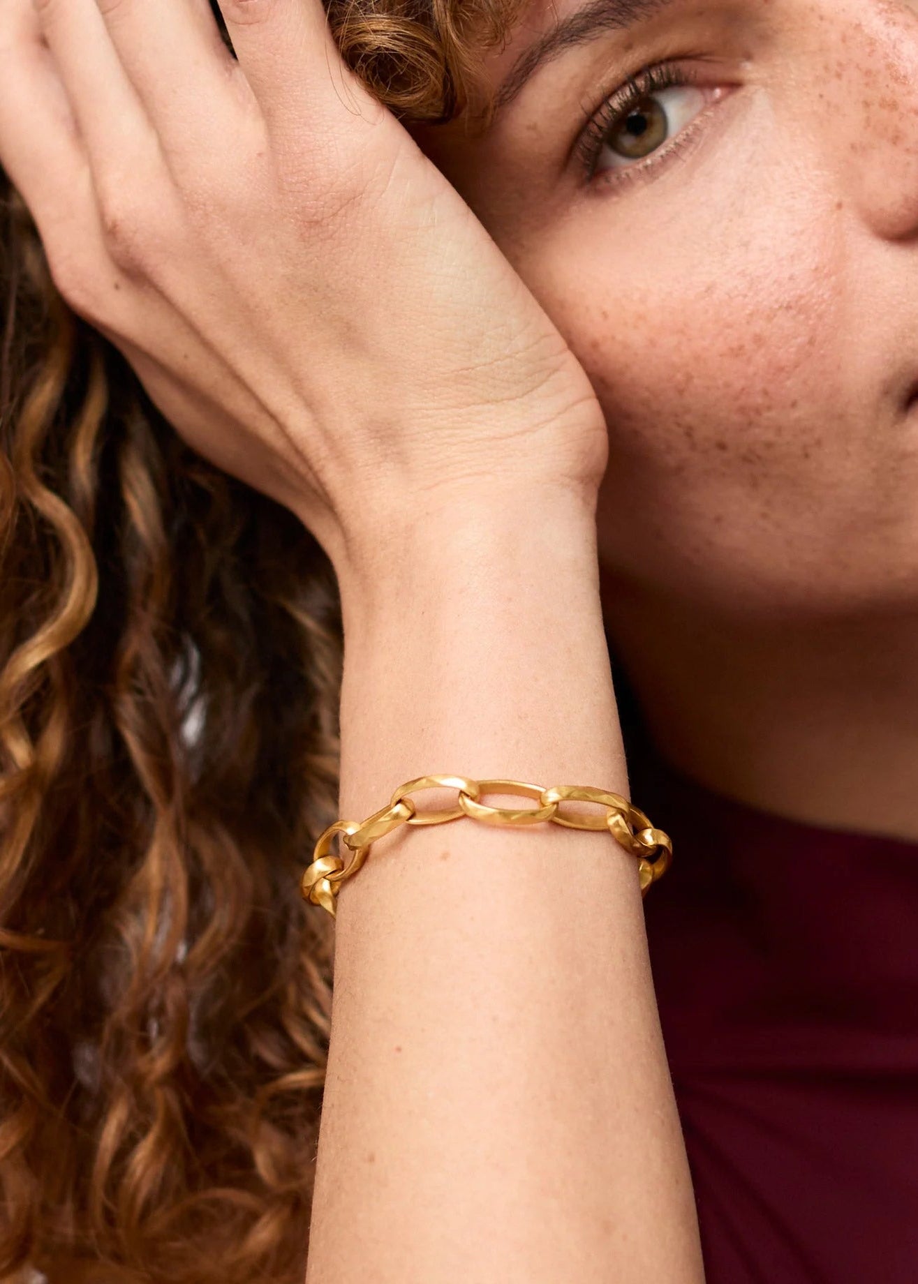 Woman wearing a gold bracelet with a neutral background