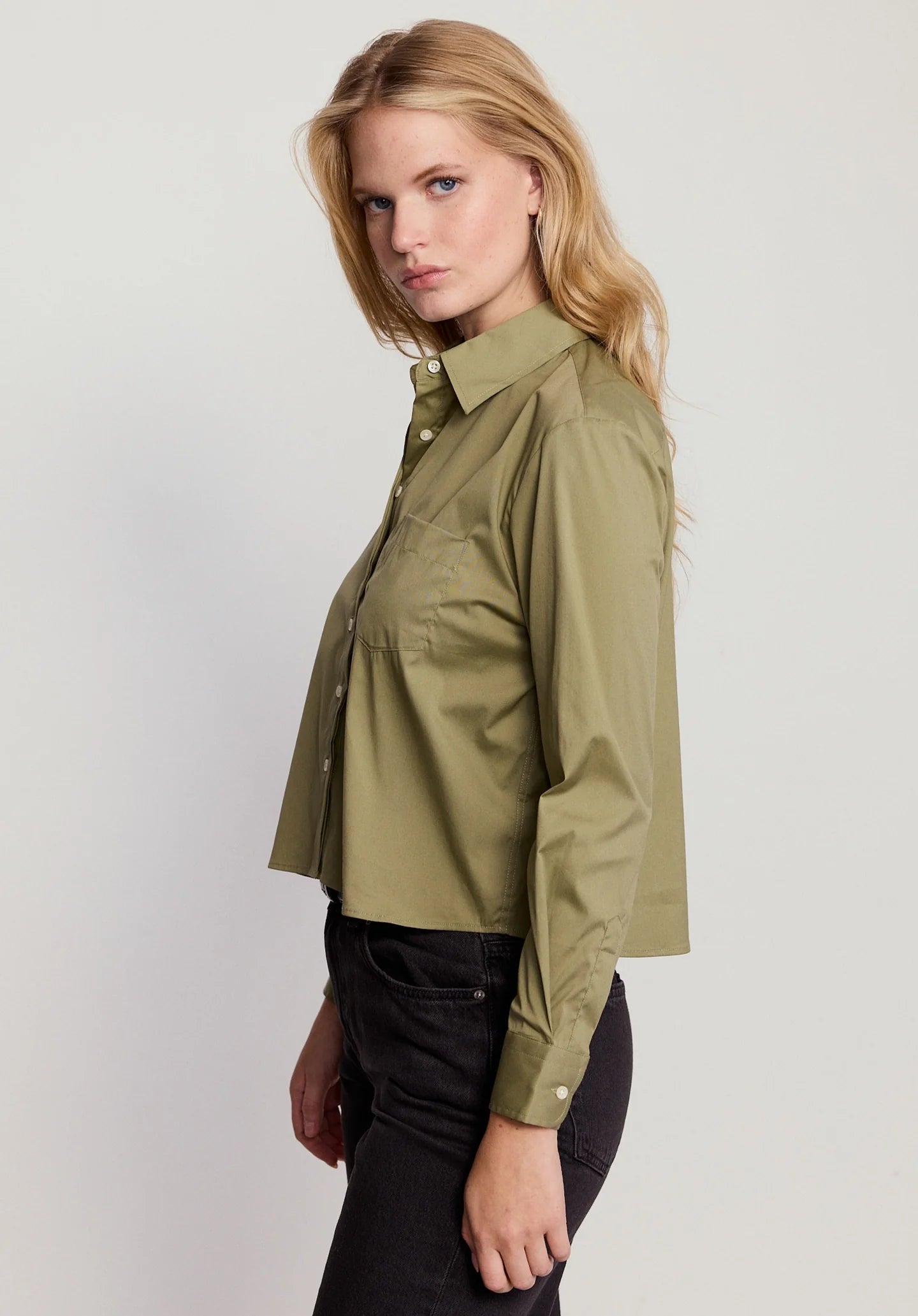 Woman wearing an olive green shirt on a light gray background