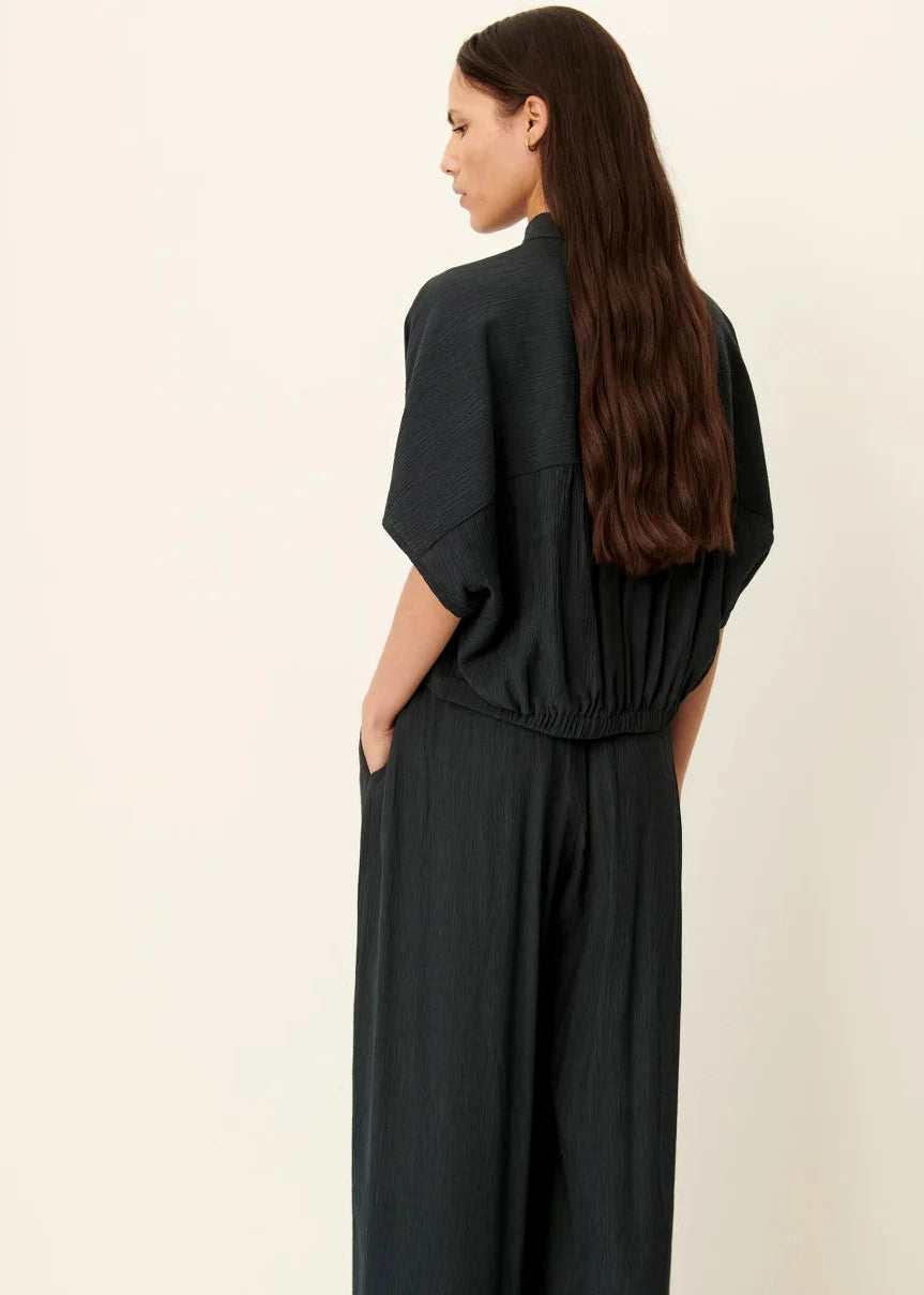 Woman wearing a black dress against a beige background