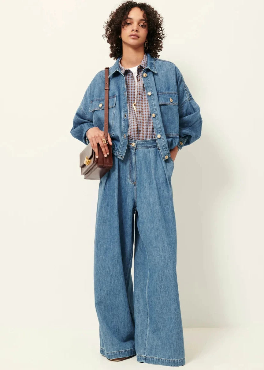 Person wearing a denim outfit with wide-leg jeans and jacket on a white background