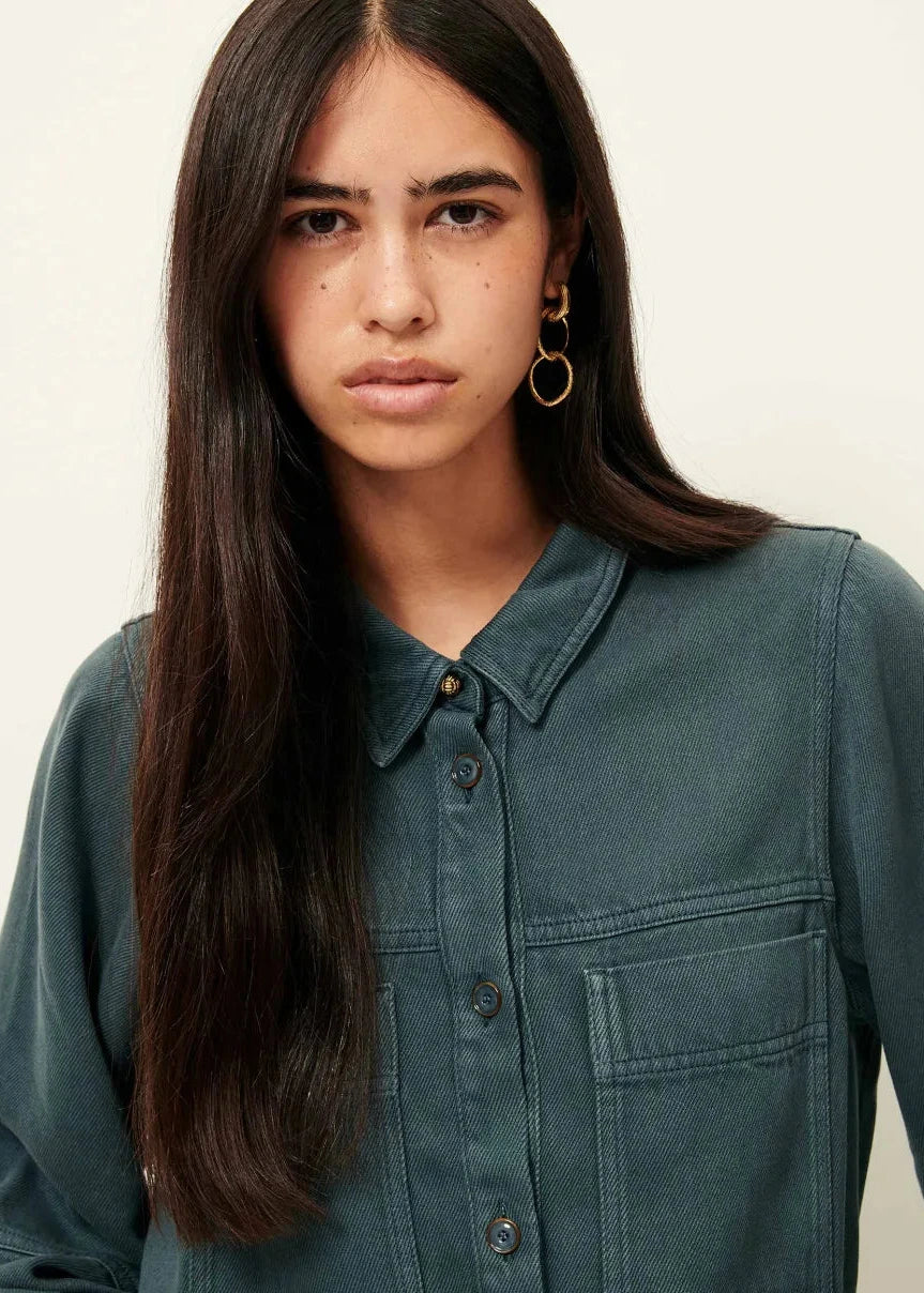 Woman wearing a teal shirt against a plain background