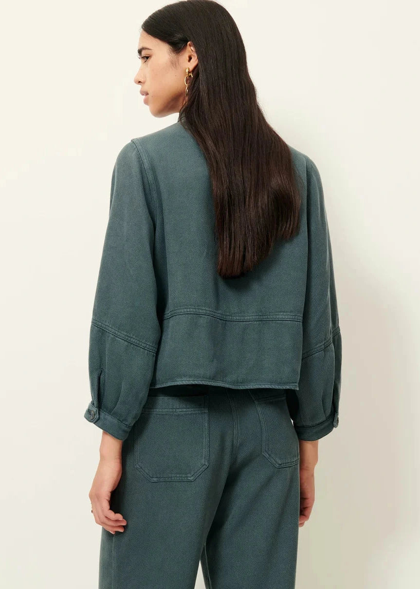 Person wearing a teal jacket and pants on a plain background