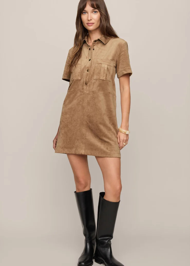 Woman wearing a brown dress with short sleeves and black boots on a beige background