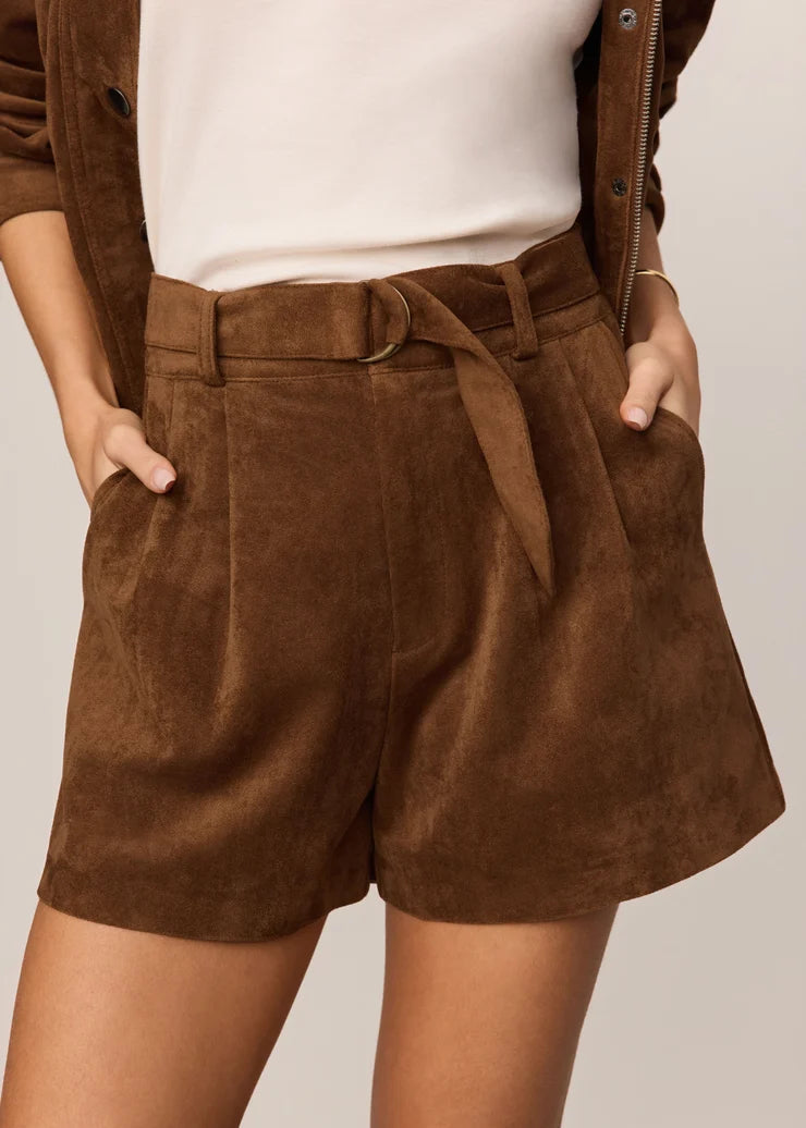 Brown suede shorts worn by a person on a plain background