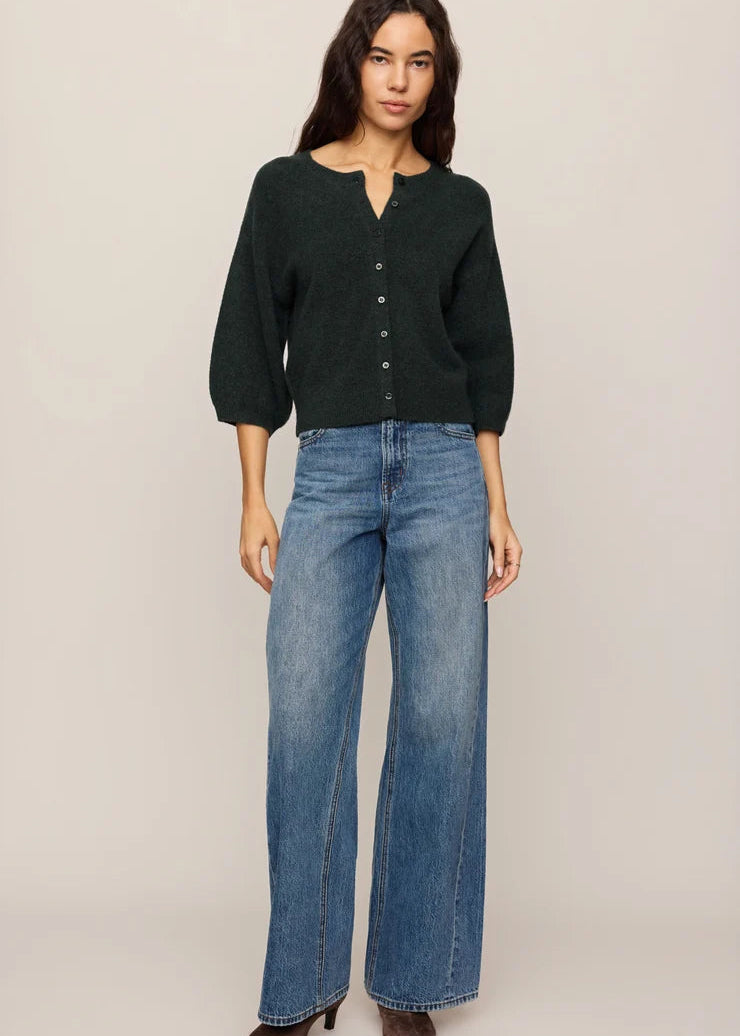 Woman wearing a black cardigan and blue jeans on a beige background