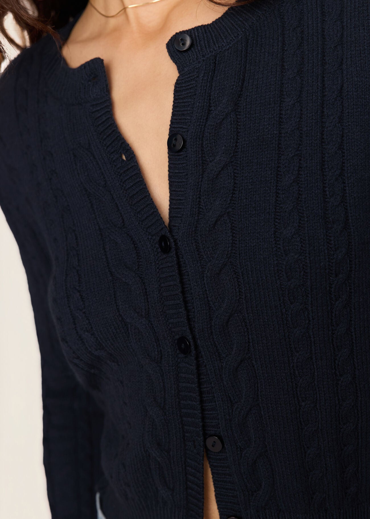 Navy blue cable knit cardigan with buttons on a plain background