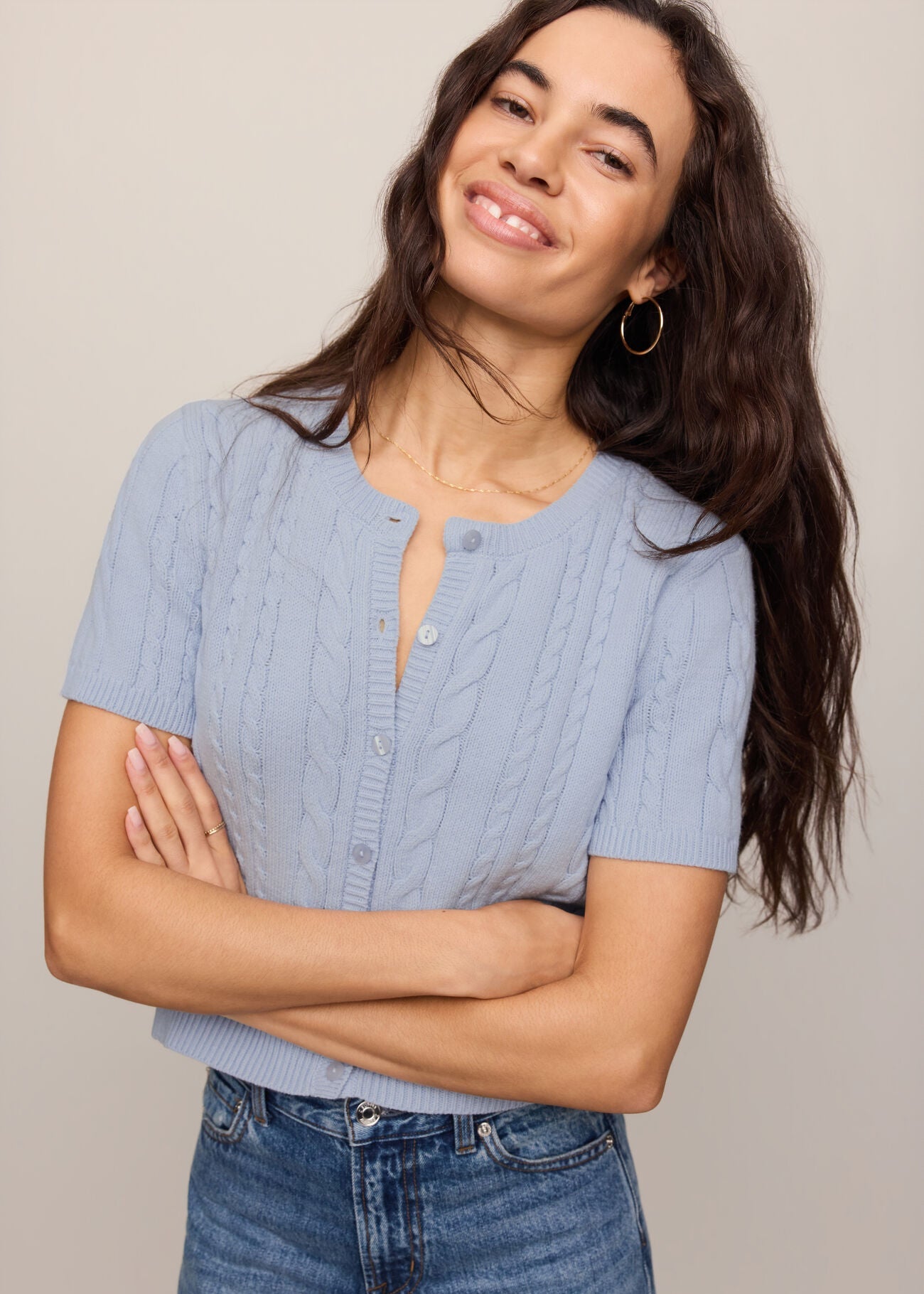 Woman wearing a light blue textured shirt and jeans against a neutral background