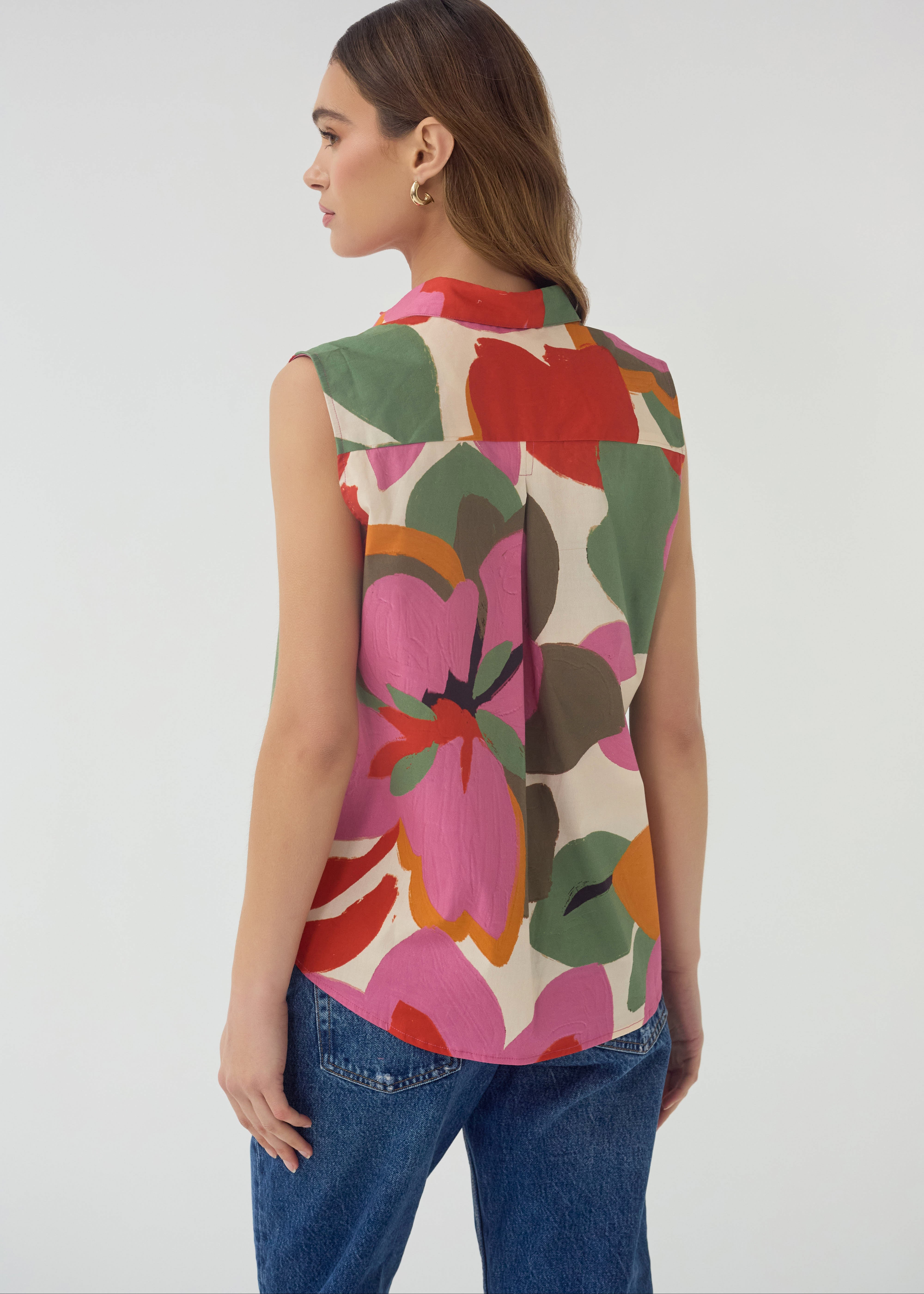 Woman wearing a sleeveless floral top with a white background