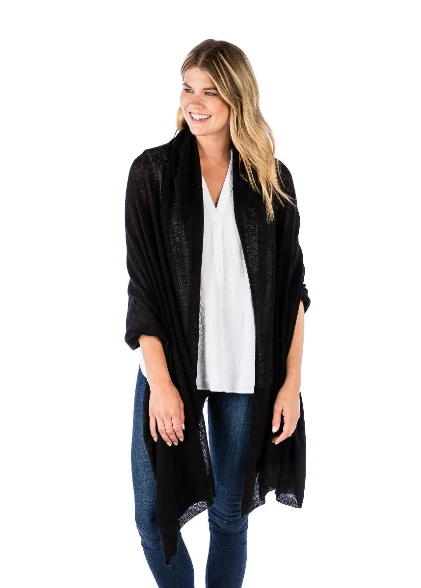 Woman wearing a black cardigan over a white shirt and blue jeans on a white background