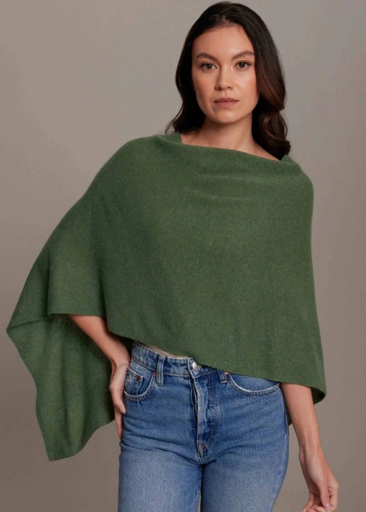 Woman wearing a green poncho over a plain background