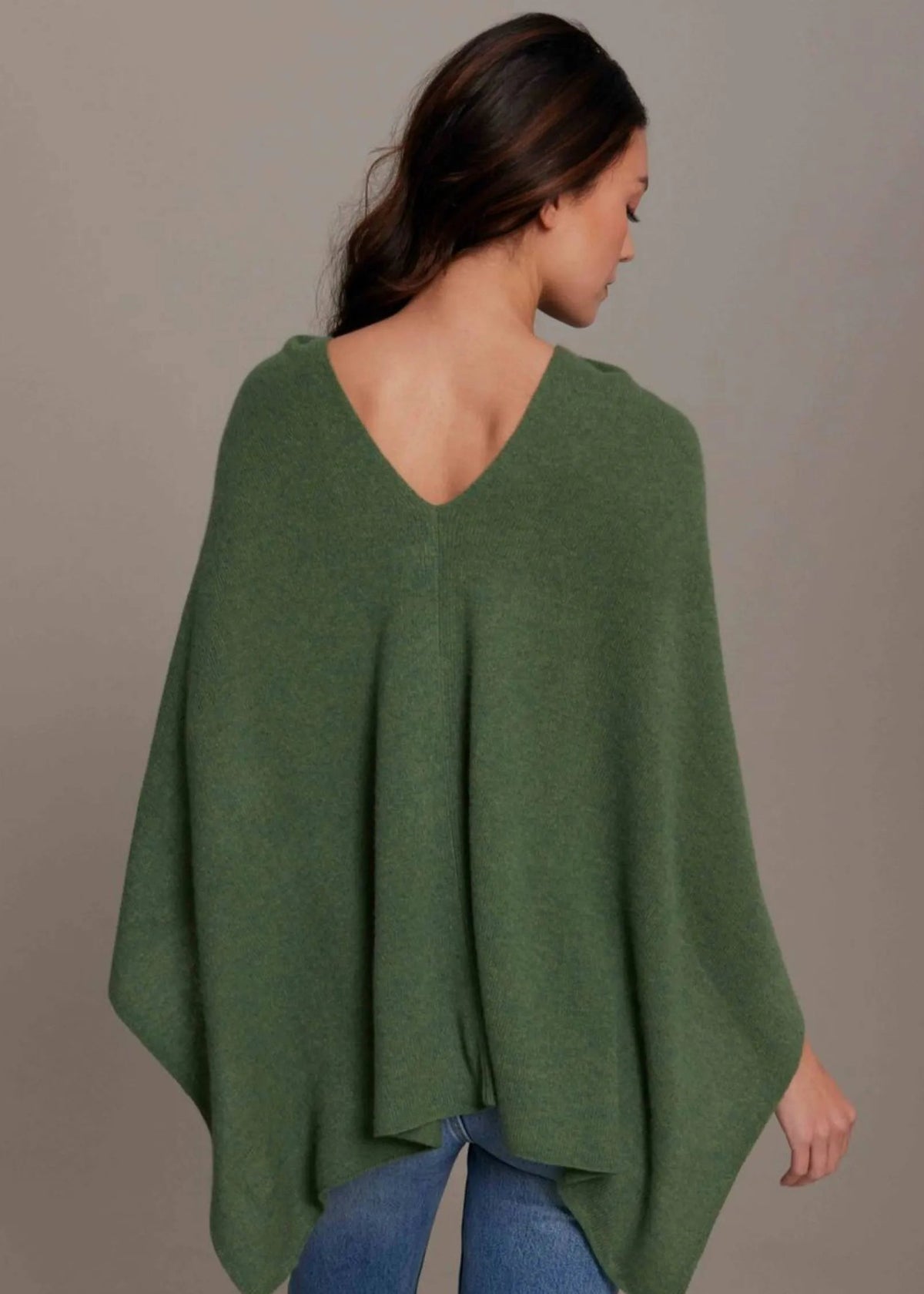 Woman wearing a green poncho against a plain background