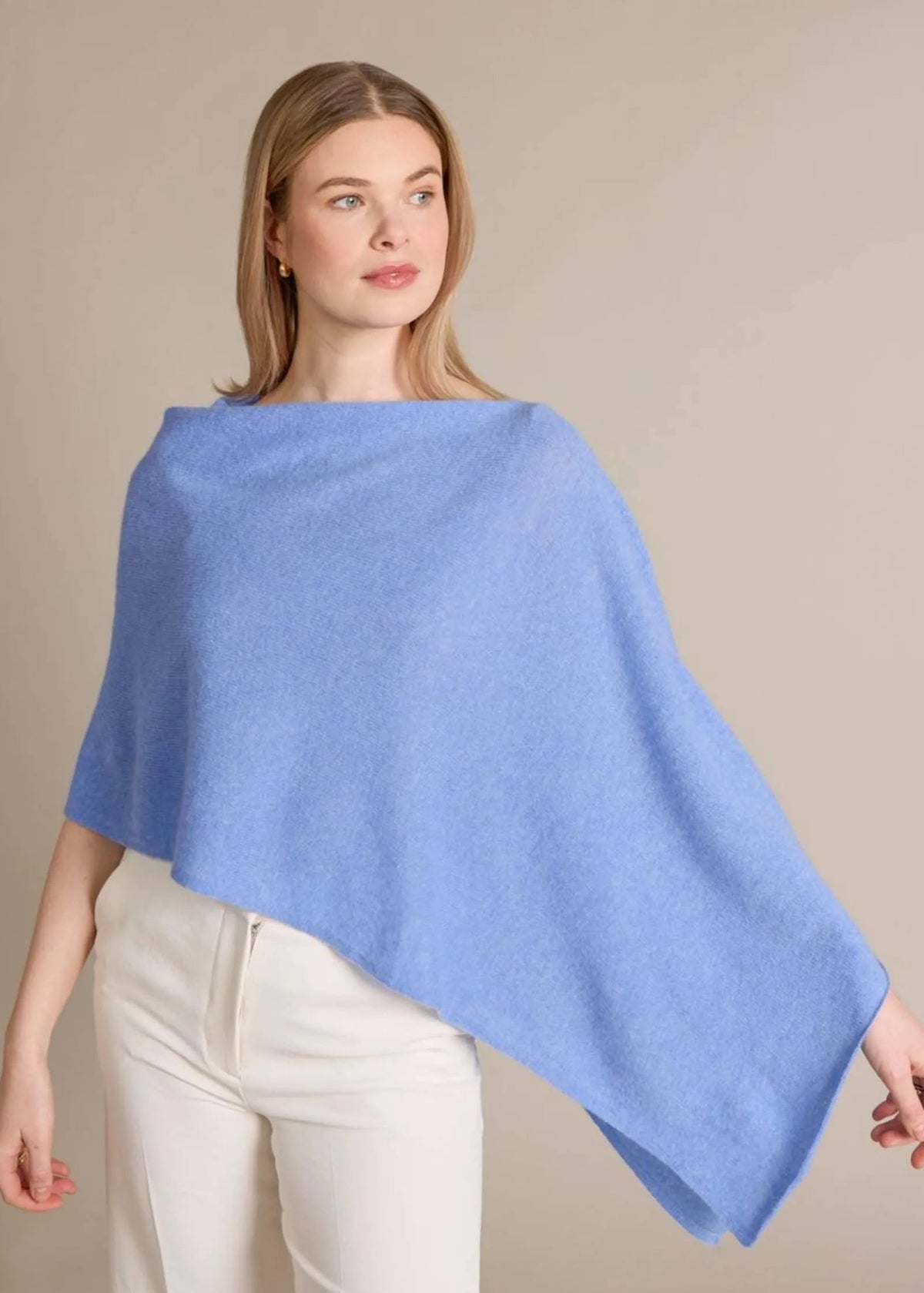 Woman wearing a light blue poncho against a beige background