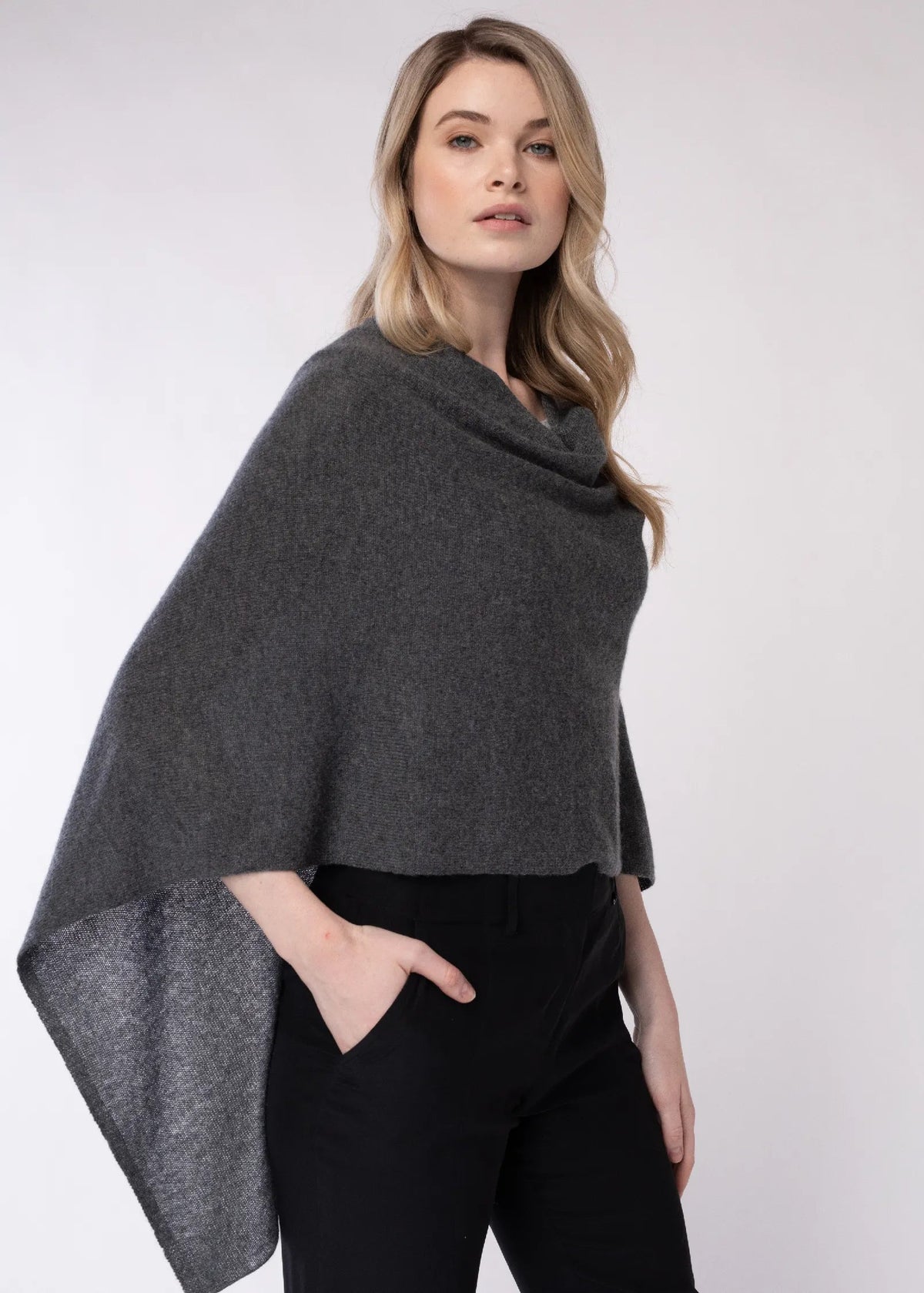Woman wearing a gray poncho against a white background