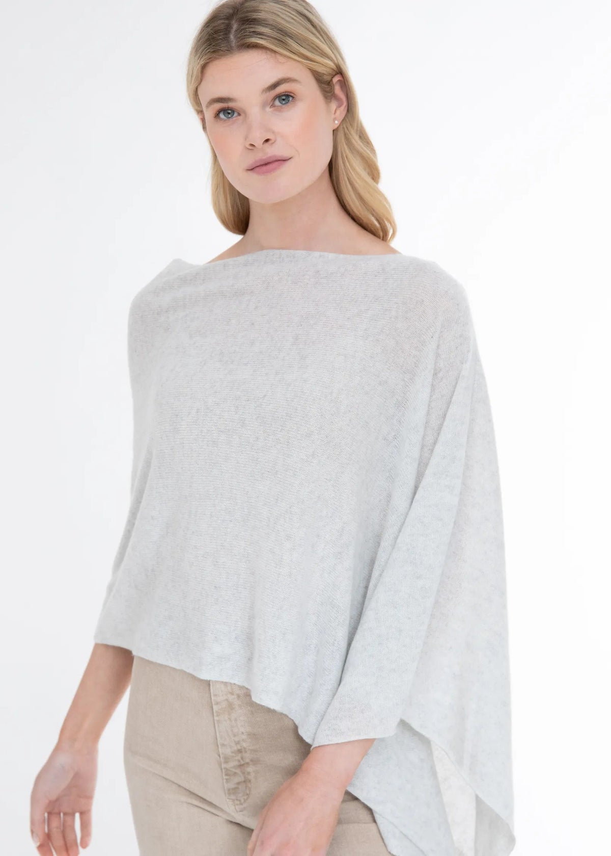 Woman wearing a light gray poncho on a white background
