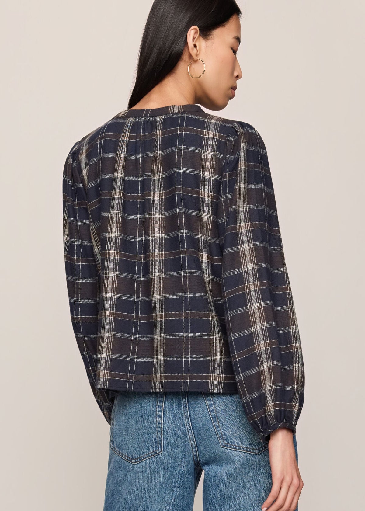 Person wearing a plaid shirt and jeans on a plain background