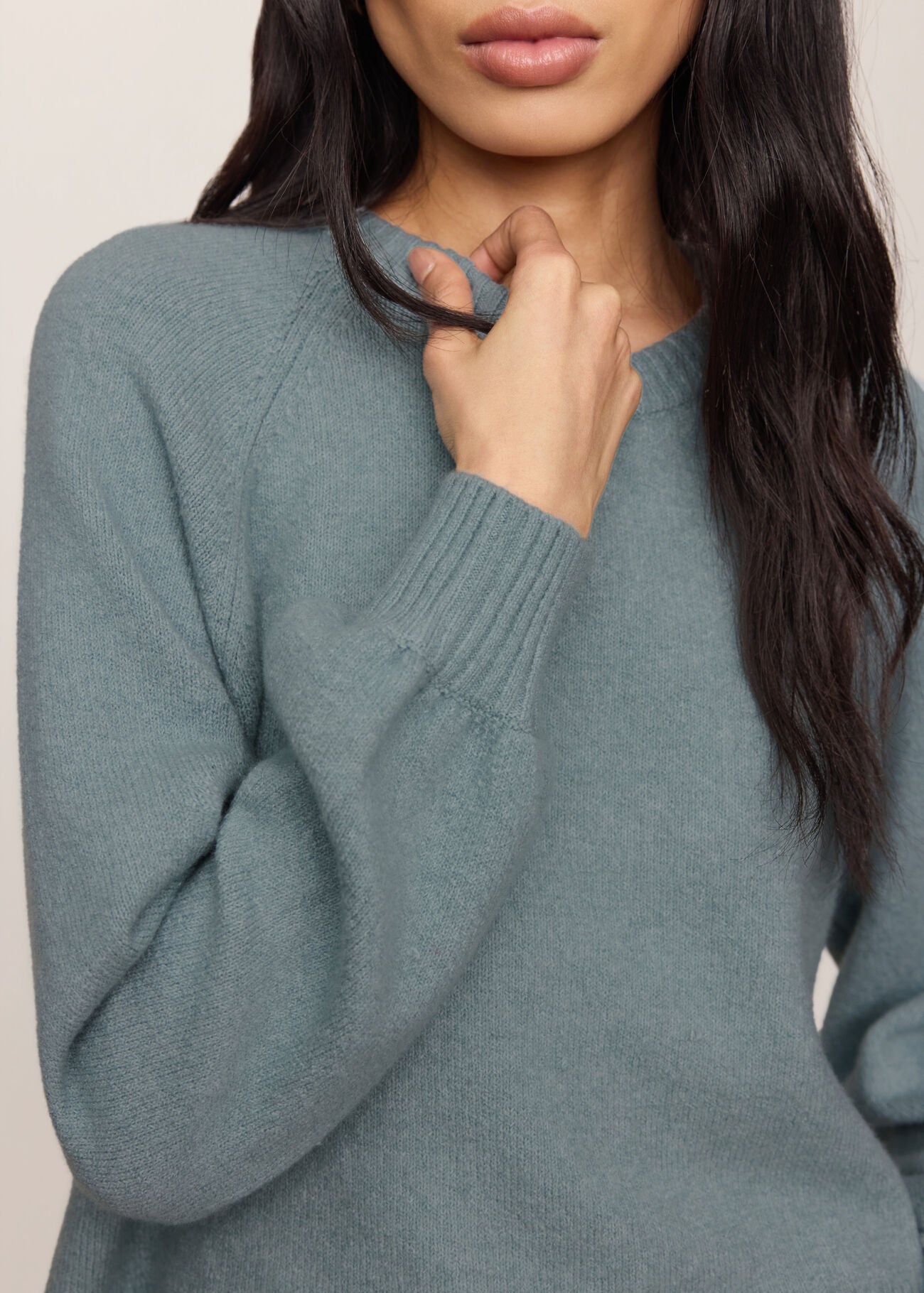 Person wearing a teal sweater with a neutral background