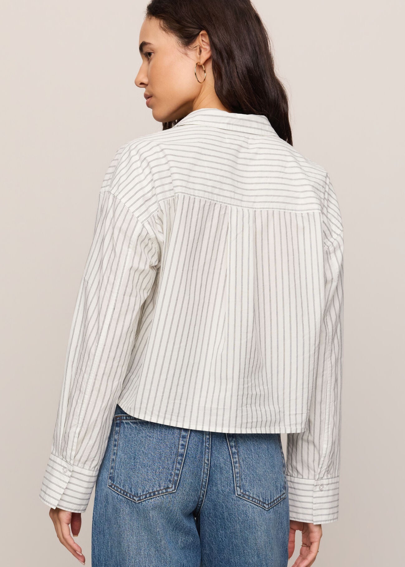 Person wearing a striped shirt and jeans against a plain background